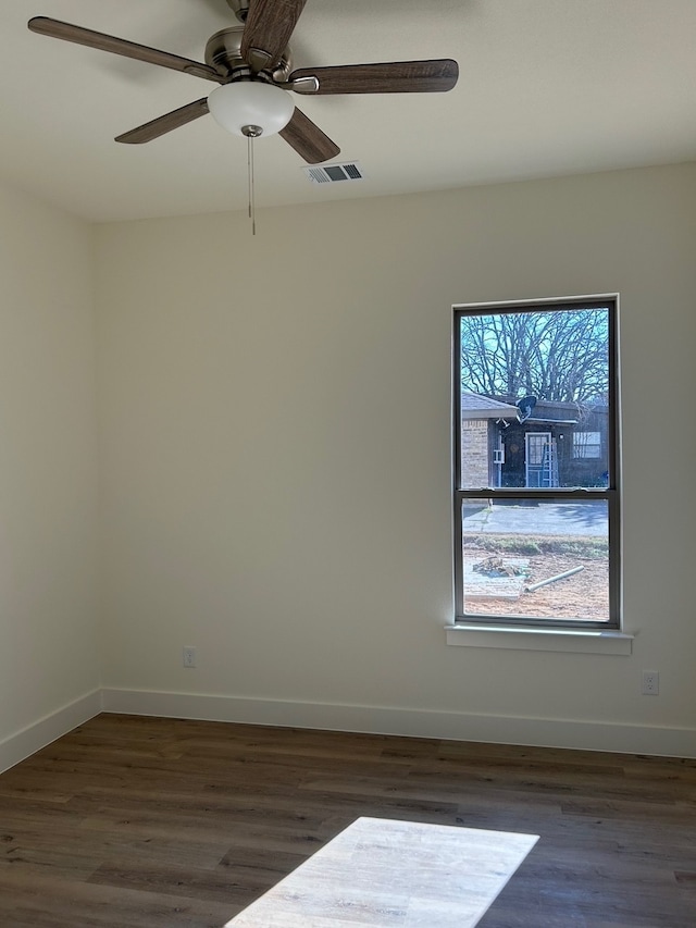 spare room featuring wood finished floors, visible vents, and baseboards