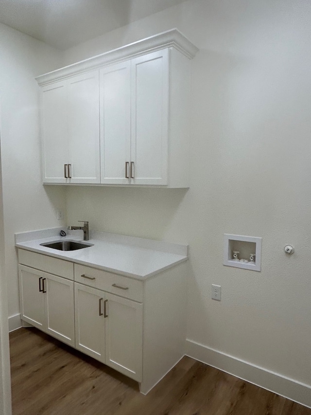 clothes washing area with cabinet space, baseboards, dark wood-type flooring, hookup for a washing machine, and a sink