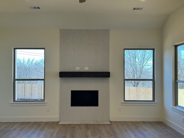 unfurnished living room with ceiling fan, lofted ceiling, a fireplace, and light hardwood / wood-style flooring