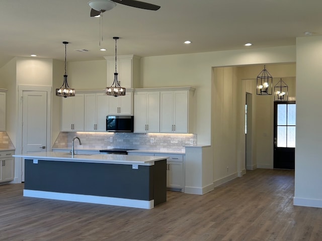 kitchen featuring light countertops, stainless steel microwave, a sink, and white cabinets