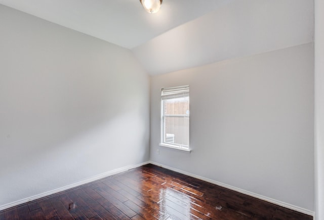 unfurnished room featuring lofted ceiling and dark hardwood / wood-style floors