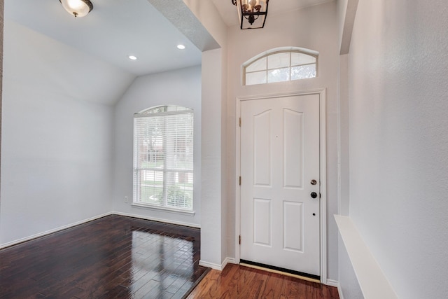 entrance foyer featuring hardwood / wood-style floors, a chandelier, and vaulted ceiling