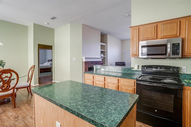 kitchen with a kitchen island, black / electric stove, a fireplace, light hardwood / wood-style floors, and built in shelves