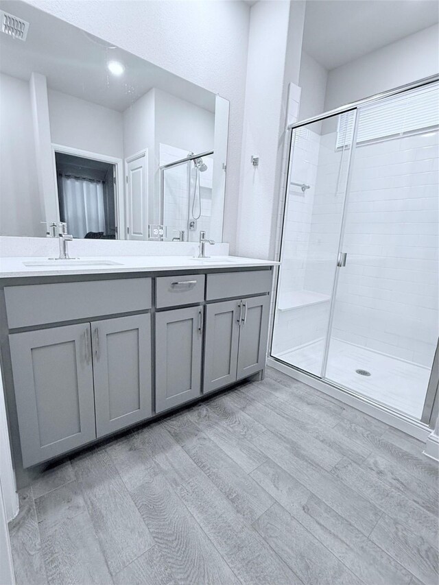 bathroom featuring vanity, a shower with shower door, and wood-type flooring