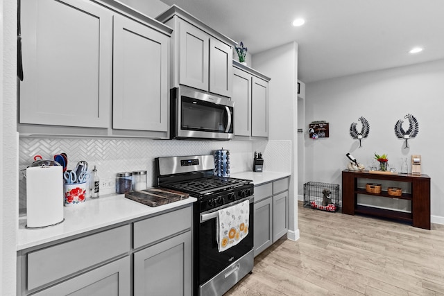 kitchen featuring tasteful backsplash, stainless steel appliances, gray cabinets, and light hardwood / wood-style floors