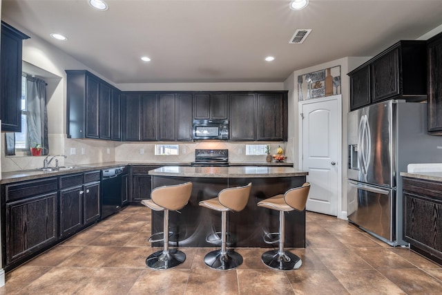 kitchen featuring a kitchen bar, sink, black appliances, a center island, and backsplash