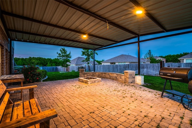 patio terrace at dusk featuring an outdoor fire pit and a grill