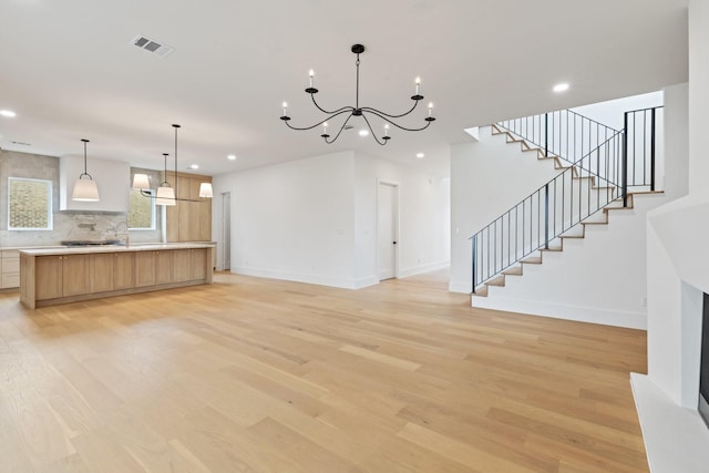 unfurnished living room with a chandelier and light hardwood / wood-style flooring