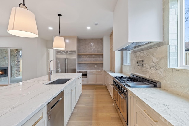 kitchen with backsplash, premium range hood, pendant lighting, sink, and high end appliances