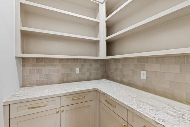 kitchen featuring light stone counters, cream cabinets, and tasteful backsplash