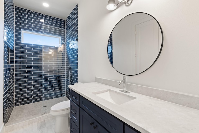 bathroom featuring toilet, vanity, tile patterned flooring, and tiled shower