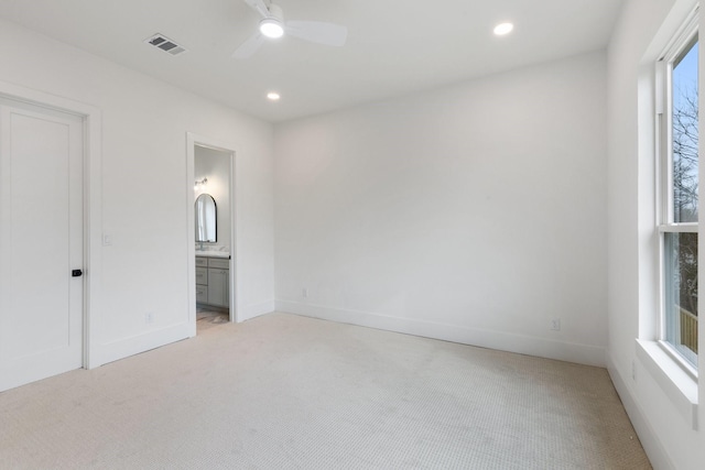 unfurnished bedroom with ceiling fan, light colored carpet, and ensuite bath