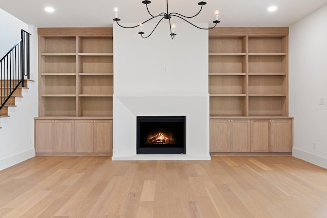 unfurnished living room with light wood-type flooring and a chandelier