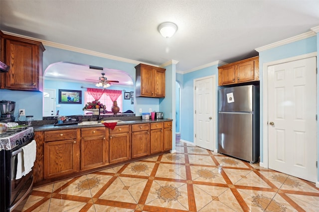 kitchen with light tile patterned floors, ceiling fan, appliances with stainless steel finishes, crown molding, and sink