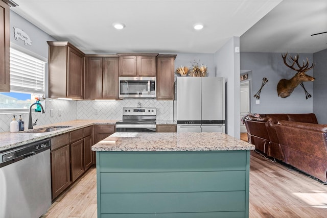 kitchen with sink, appliances with stainless steel finishes, a center island, and tasteful backsplash