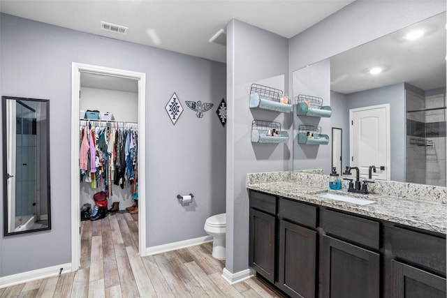 bathroom featuring vanity, toilet, wood-type flooring, and a shower with door