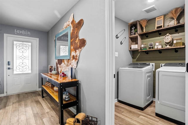 clothes washing area with washing machine and dryer and light hardwood / wood-style flooring