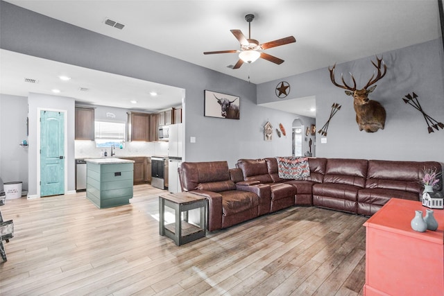 living room with light hardwood / wood-style floors, sink, and ceiling fan