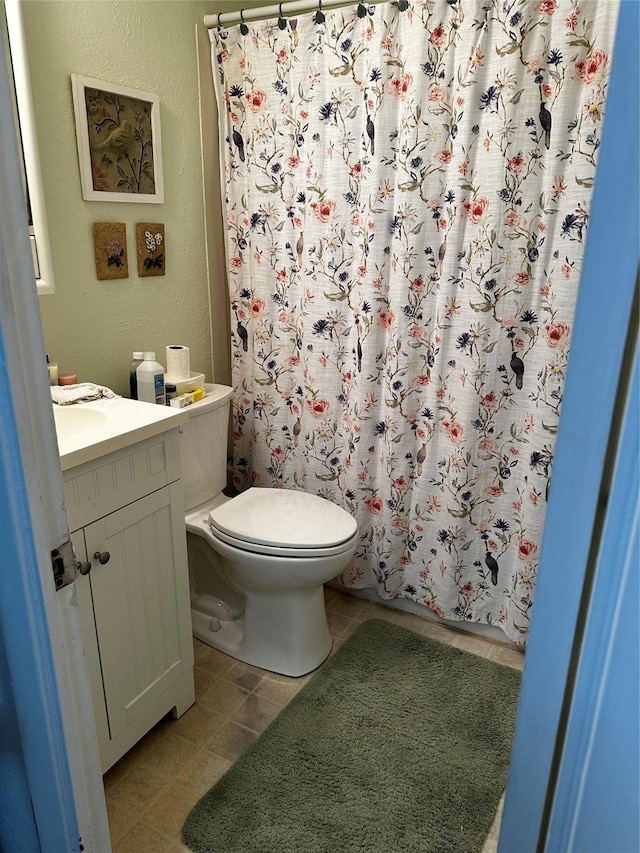 bathroom featuring tile patterned flooring, toilet, vanity, and a shower with shower curtain