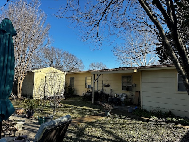 rear view of house with a lawn and a storage shed