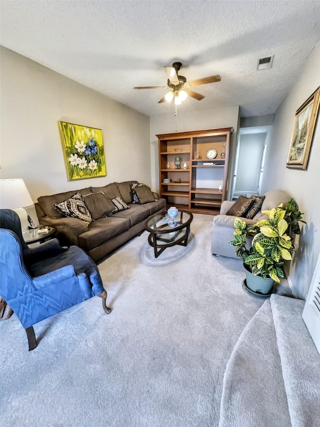 living room with a textured ceiling, ceiling fan, and carpet flooring