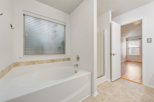 bathroom with tile patterned floors, a textured ceiling, and shower with separate bathtub