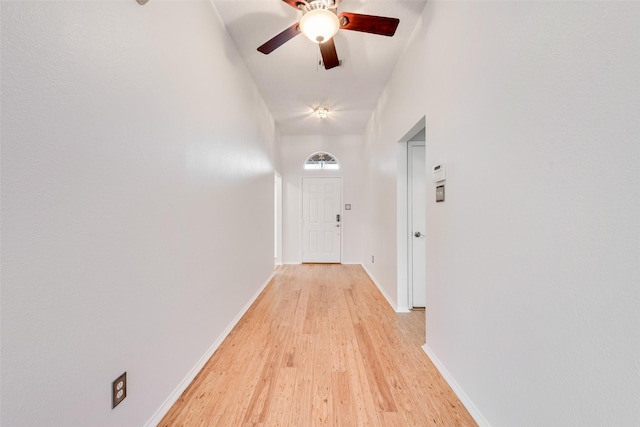 hallway featuring a towering ceiling and light wood-type flooring