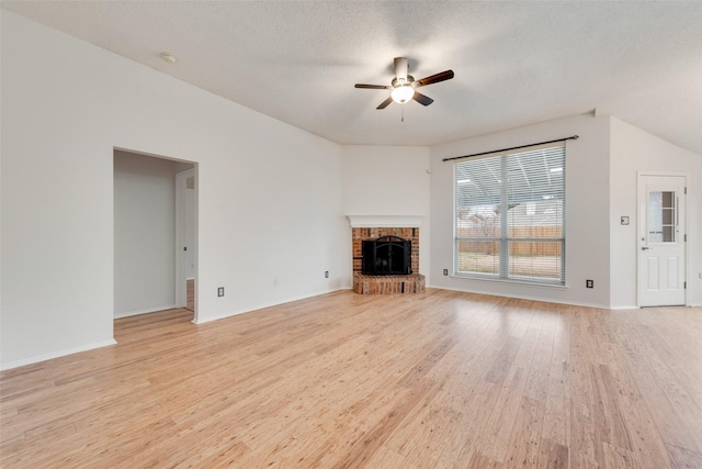 unfurnished living room with ceiling fan, lofted ceiling, a fireplace, a textured ceiling, and light hardwood / wood-style flooring