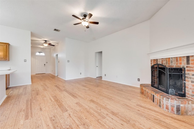 unfurnished living room featuring a brick fireplace, light hardwood / wood-style flooring, and ceiling fan