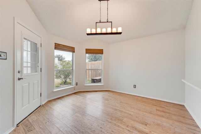 unfurnished dining area with light wood-type flooring, a chandelier, and lofted ceiling