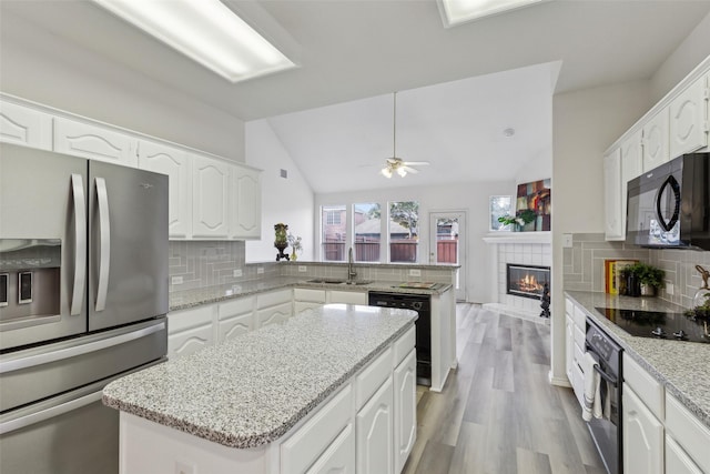 kitchen featuring sink, white cabinetry, a kitchen island, decorative backsplash, and black appliances