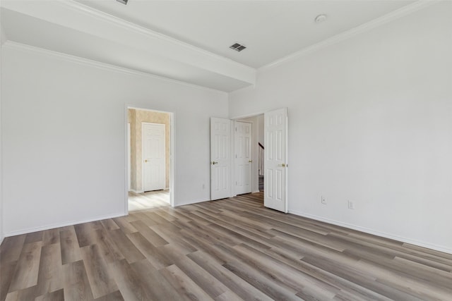 spare room featuring a high ceiling, ornamental molding, and light hardwood / wood-style flooring