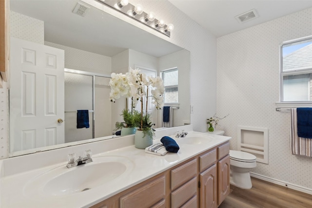 bathroom featuring a shower with door, a healthy amount of sunlight, hardwood / wood-style floors, and toilet