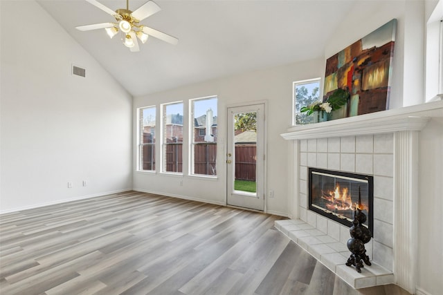 unfurnished living room with ceiling fan, a fireplace, high vaulted ceiling, and light wood-type flooring