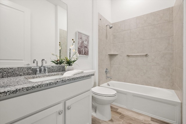 full bathroom with vanity, tiled shower / bath combo, toilet, and hardwood / wood-style flooring