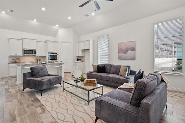 living room featuring light hardwood / wood-style flooring, vaulted ceiling, and ceiling fan