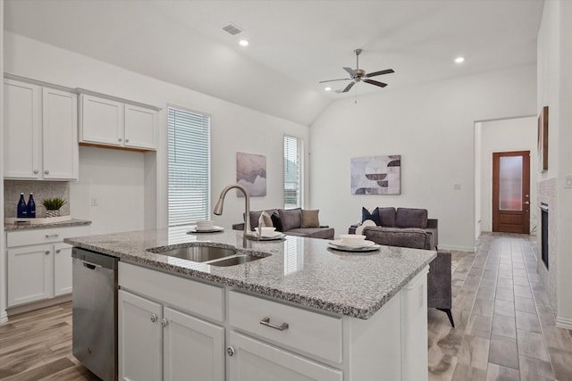 kitchen with stainless steel dishwasher, an island with sink, sink, and white cabinets