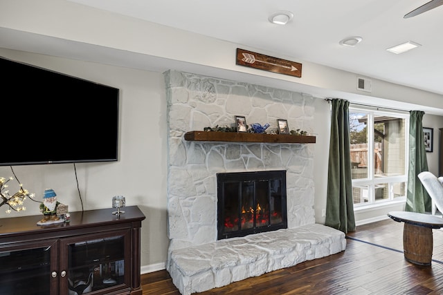 living room with baseboards, a fireplace, visible vents, and wood finished floors