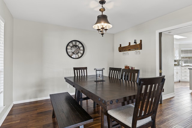 dining space with a notable chandelier, hardwood / wood-style flooring, and baseboards