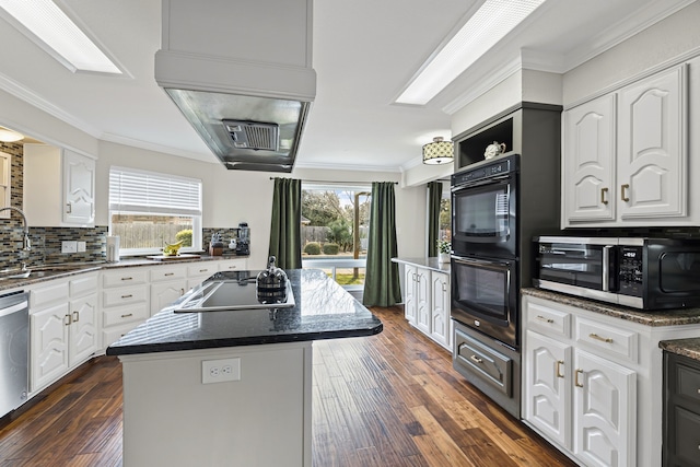 kitchen with black appliances, a kitchen island, ornamental molding, and a sink