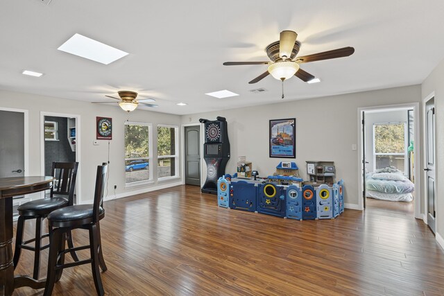 playroom with a skylight, dark hardwood / wood-style floors, and ceiling fan