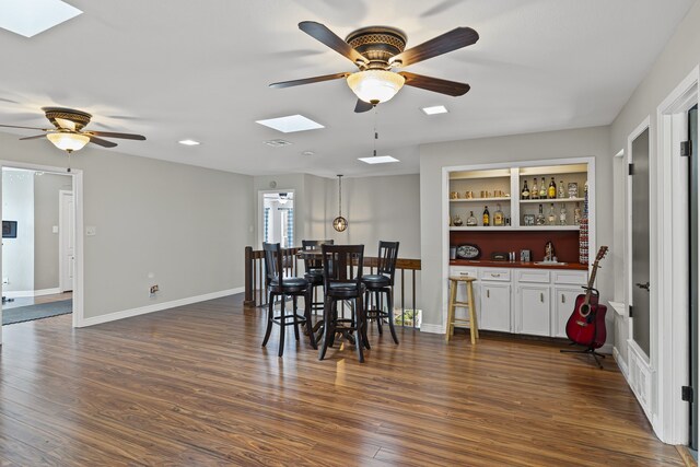 dining room featuring built in shelves, ceiling fan, indoor bar, and dark hardwood / wood-style floors