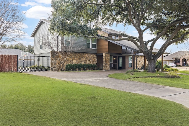 view of front of home featuring driveway, stone siding, and a front lawn