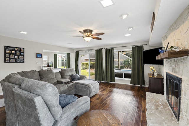 living area with ceiling fan, a fireplace, and dark wood finished floors