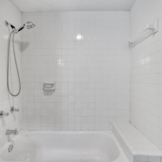 bathroom featuring a textured ceiling and tiled shower / bath combo