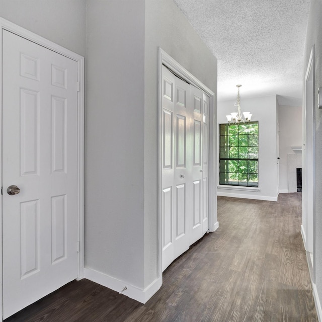 hallway with dark hardwood / wood-style flooring, a chandelier, and a textured ceiling