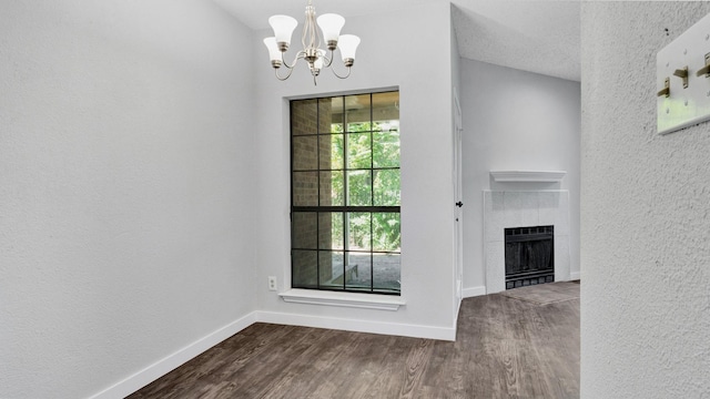 interior space with a tiled fireplace, dark hardwood / wood-style floors, and a notable chandelier