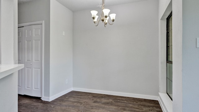 unfurnished dining area with a textured ceiling, a chandelier, and dark hardwood / wood-style flooring