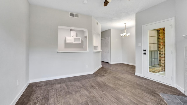 spare room featuring a textured ceiling, ceiling fan with notable chandelier, and dark hardwood / wood-style floors