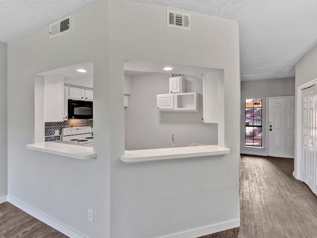 kitchen with white electric range, wood-type flooring, white cabinetry, tasteful backsplash, and kitchen peninsula